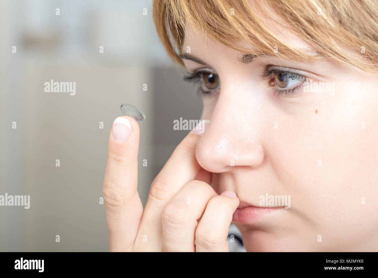 Giovane donna/ragazza mettendo la lente a contatto nel Suo occhio close up con spazio copia . Messa a fuoco selettiva. Foto Stock