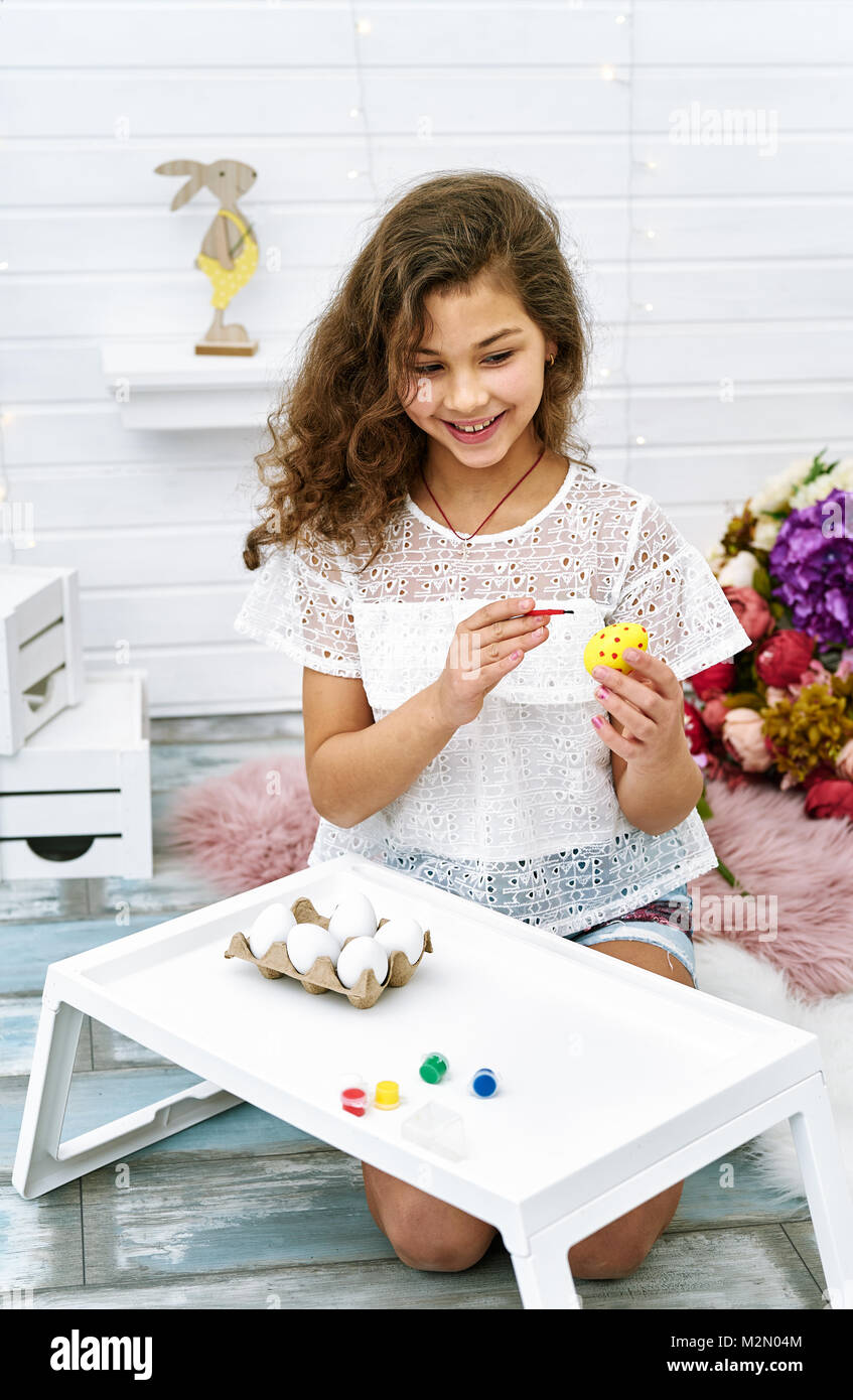 Bella dieci anni ragazza dipingere le uova di Pasqua Foto Stock