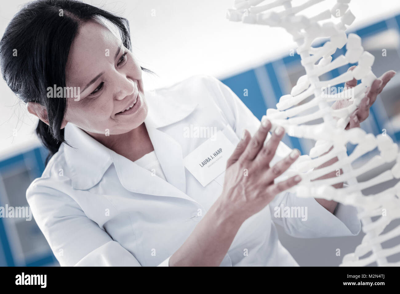 Appassionato ricercatore femmina di esaminare il modello di DNA Foto Stock