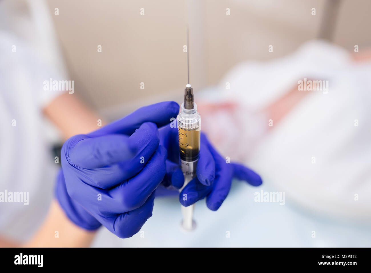 Siringa per iniezione medica in mani con guanti blu. Un infermiere o un medico. Farmaco liquido o sostanze stupefacenti. Assistenza sanitaria in ospedale. Mesoterapia ago. Vacci Foto Stock