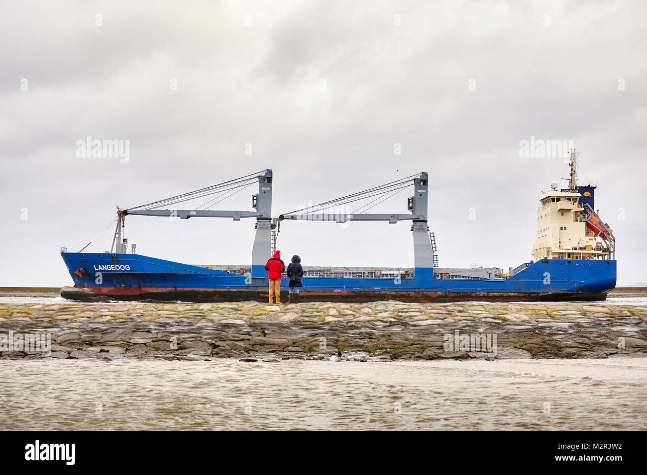 Swinoujscie, Polonia - 28 Gennaio 2018: la gente guarda Langeoog nave cargo di lasciare il porto di Swinoujscie su un nuvoloso giorno d'inverno. Foto Stock