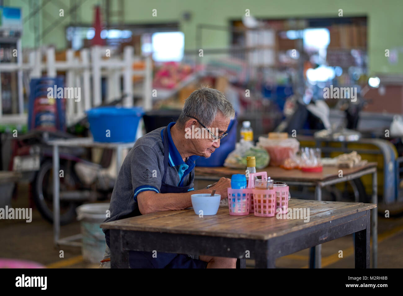 Uomo anziano di mangiare da soli. Thailandia ristorante. Senior Thai. Foto Stock