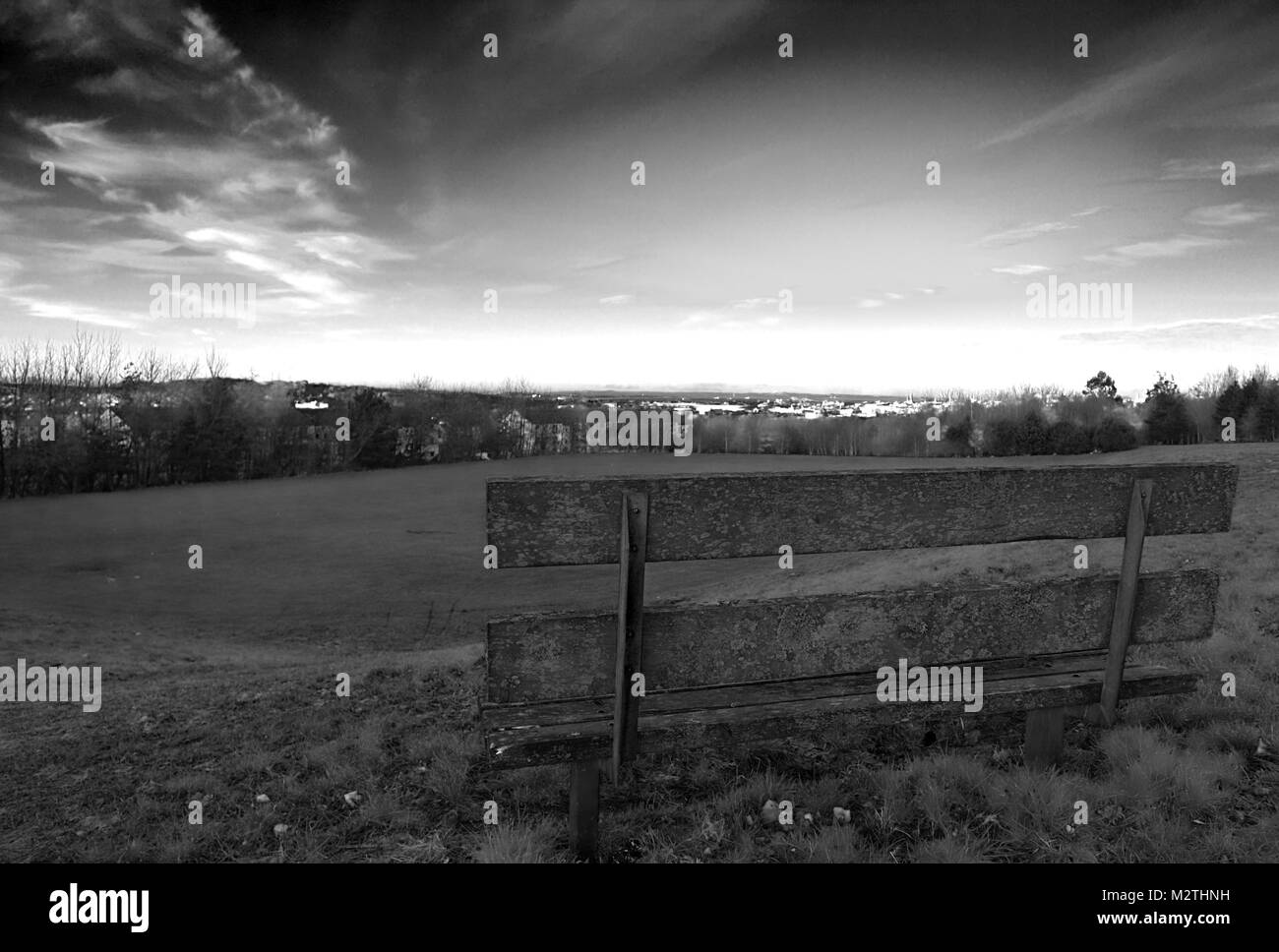 Un bianco e nero girato di una panca su Wester Hailes park al tramonto a Edimburgo, Scozia, Regno Unito Foto Stock