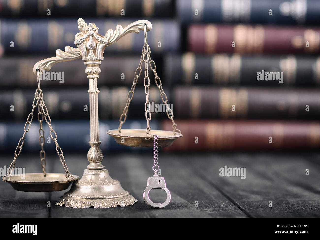 Il diritto e la giustizia, il concetto di legalità, bilancia della giustizia e manette su un nero lo sfondo di legno. Foto Stock