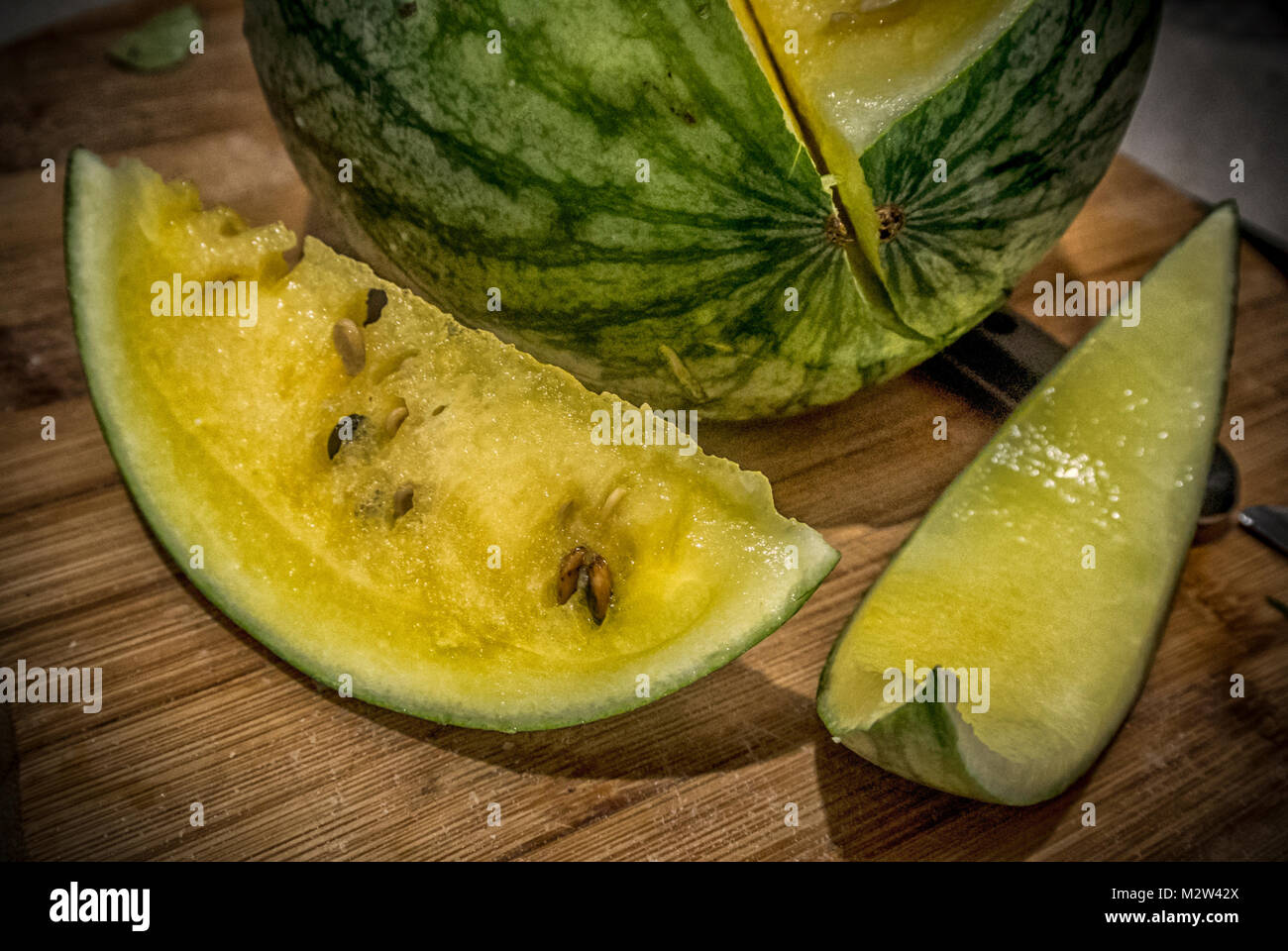 Un giallo a fette di anguria su una tavola di legno Foto Stock