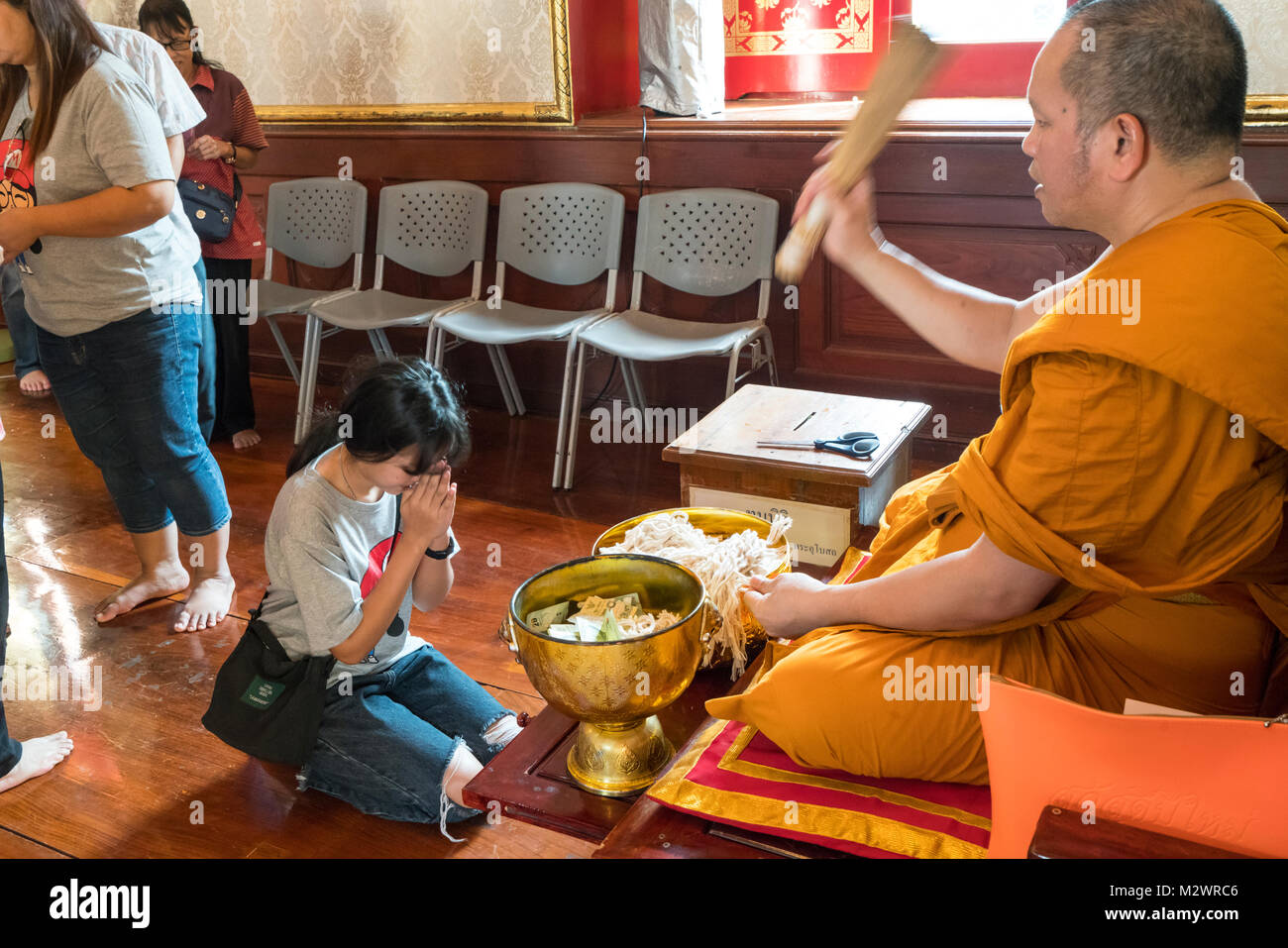 Il monaco con fedeli in Wat Traimit tempio a Bangkok Foto Stock