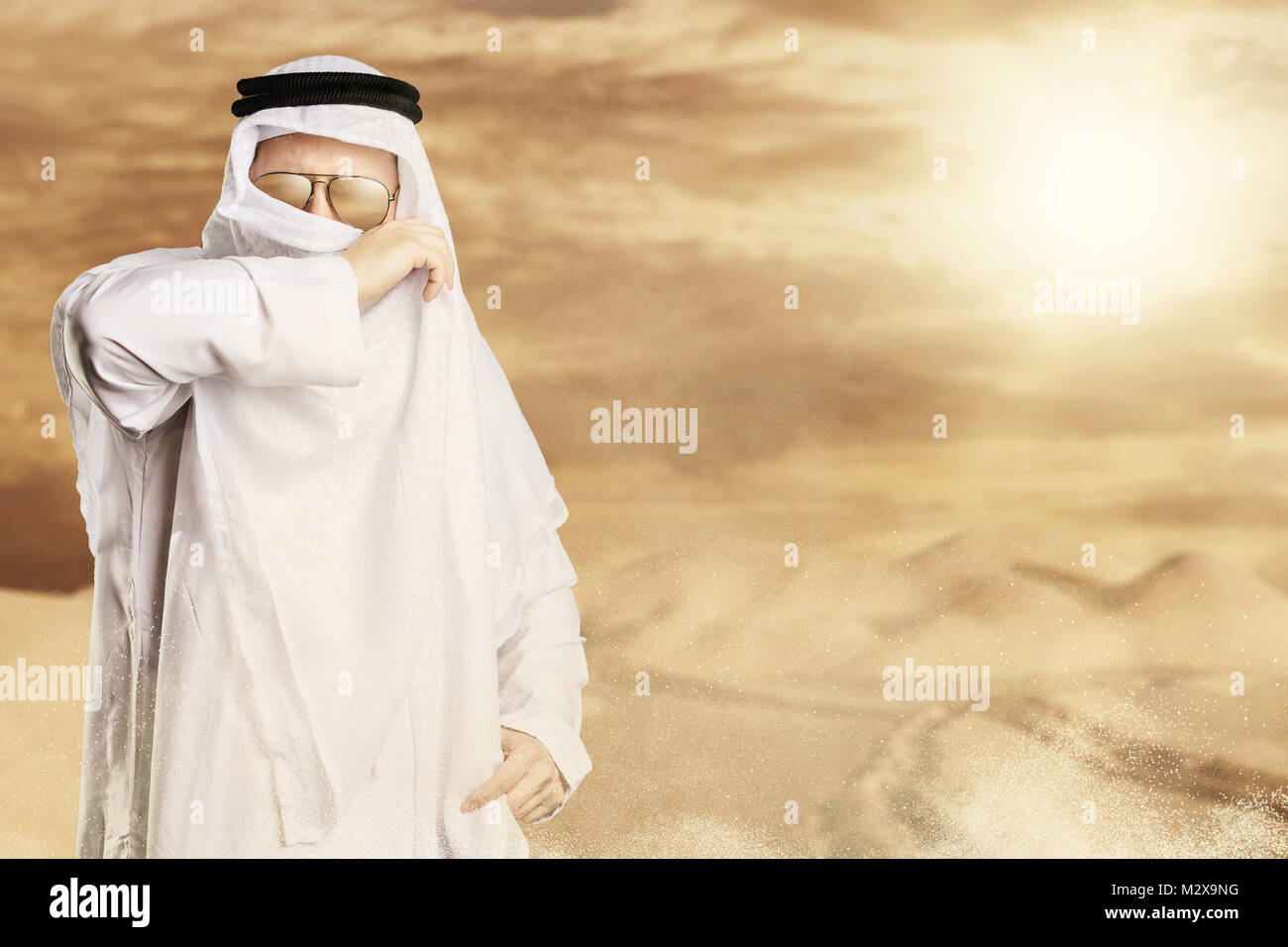 Sheik proteggere con keffiyeh dalla tempesta del deserto di fronte alla luce del sole Foto Stock