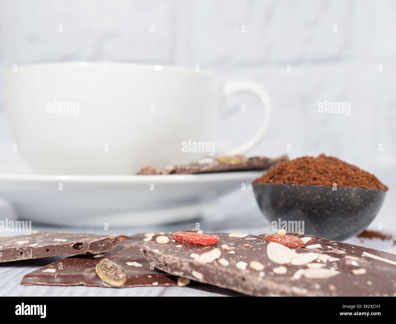 Un bianco tazza da caffè con cioccolato fondente lastre e una misura di caffè macinato Foto Stock