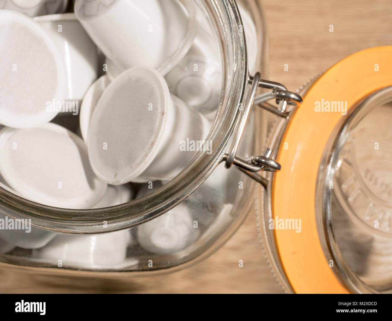 Un vaso di vetro pieno di bianco generico nespresso montare le cialde di caffè Foto Stock