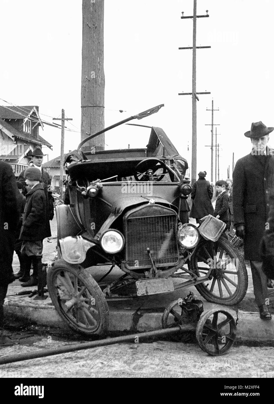 Folla si raduna attorno a un incidente di auto la scena in cui una automobile è avvolto intorno ad un palo telefonico, ca. 1924. Foto Stock