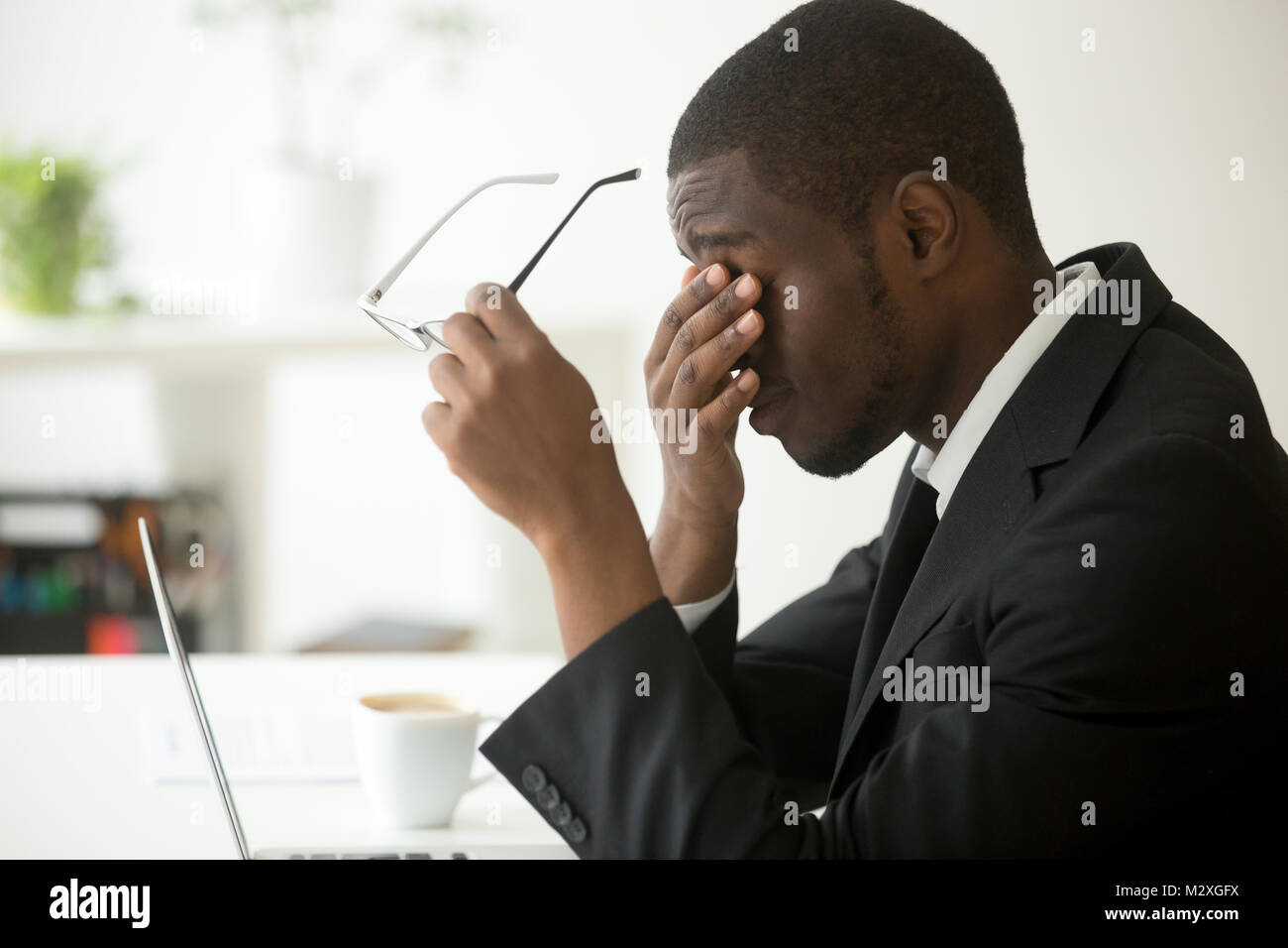 Stanco di computer imprenditore africano togliere i bicchieri si sente affaticamento della vista la stanchezza dopo un lungo lavoro di ufficio su laptop, esausto oberati di lavoro ha sottolineato depr Foto Stock