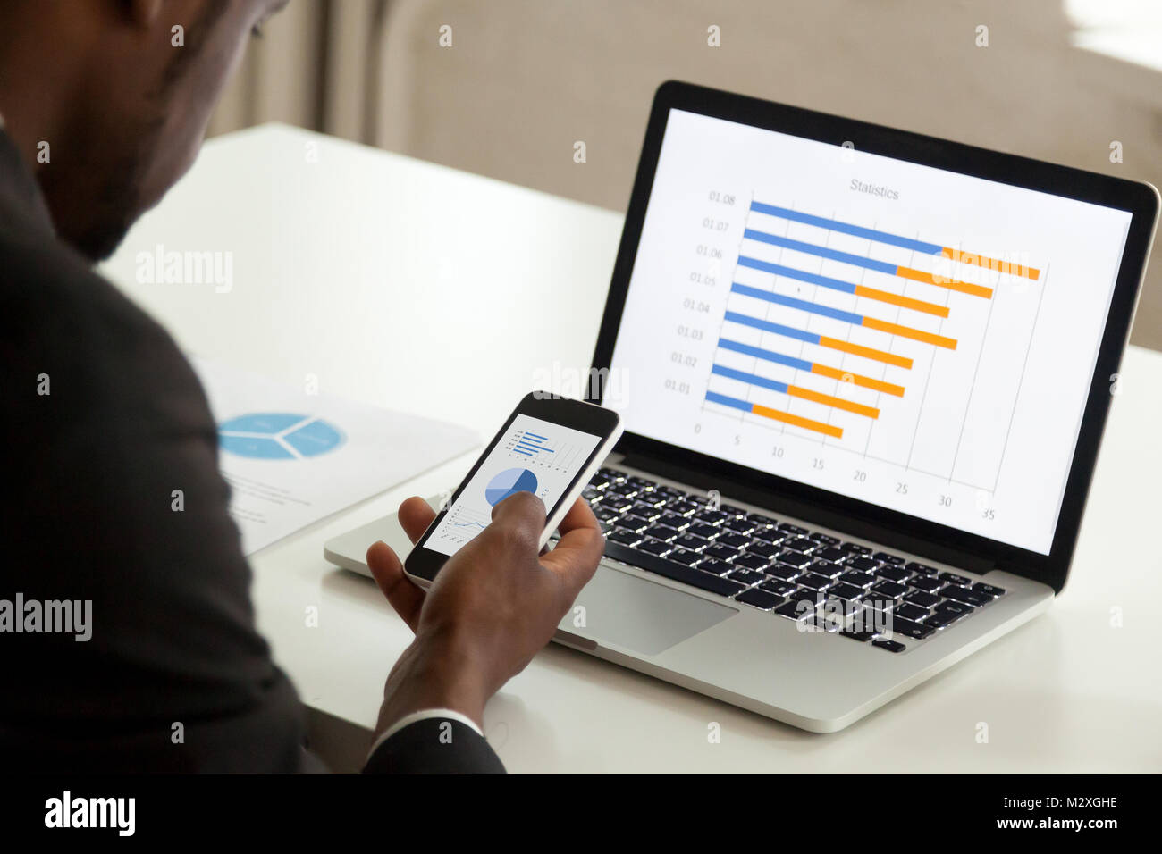 African American businessman utilizzando dispositivi per il business, nero lavoratore di ufficio azienda lavorazione dello smartphone con il computer portatile e il telefono cellulare, corporate Statistiche sulla r Foto Stock