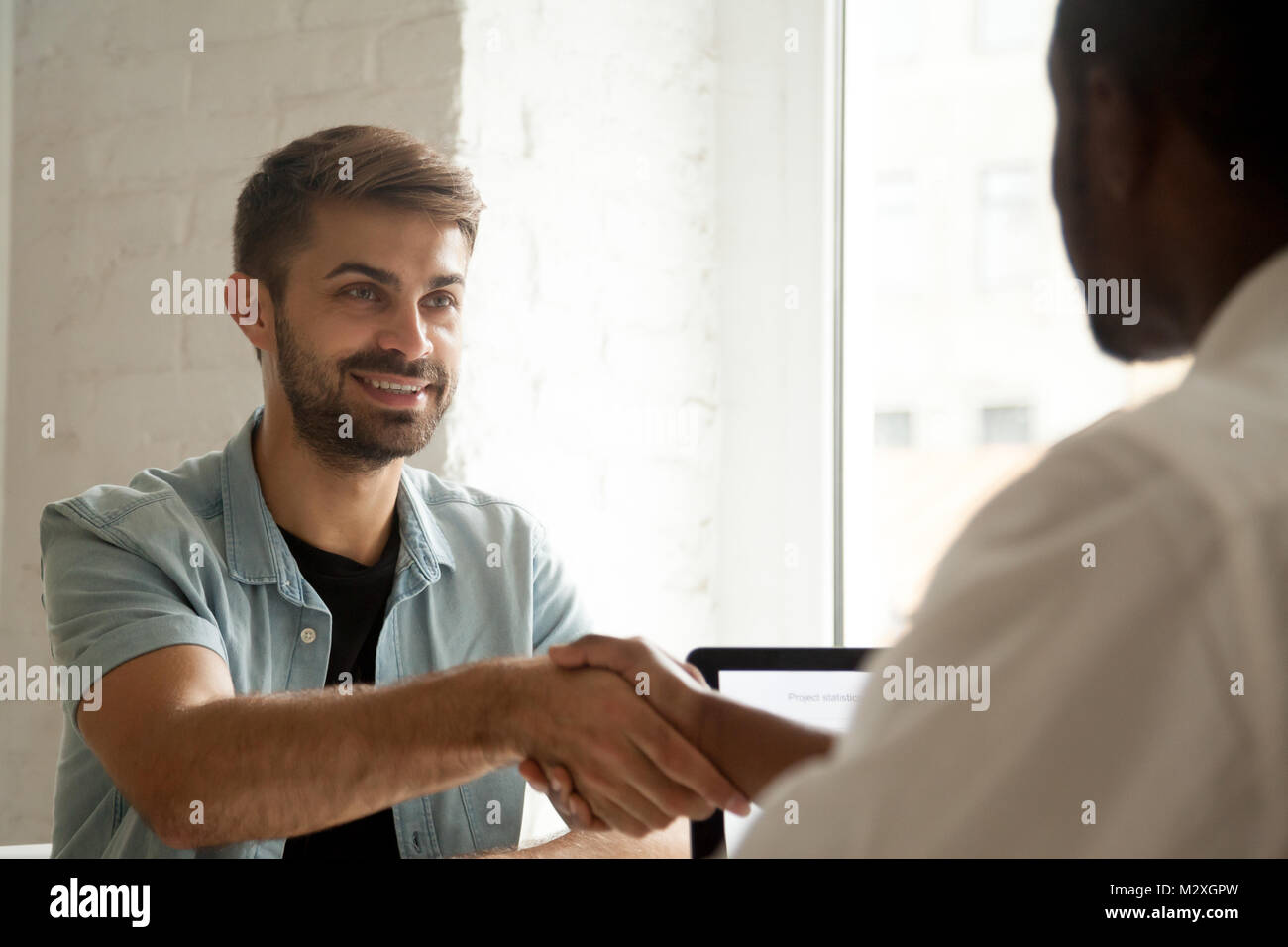 Sorridente fiducioso candidato caucasico africano di handshaking hr manager al colloquio di lavoro, l'uomo bianco client o il messaggio di saluto del cliente nero fornitore di servizio, m Foto Stock