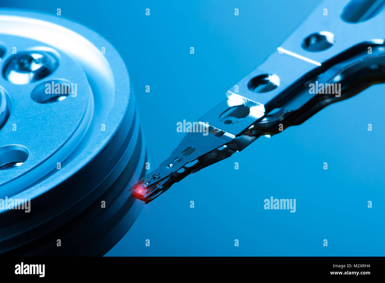 Chiudere fino all'interno di unità disco rigido. Dettaglio della scrittura/lettura di testa sul braccio attuatore e asse. Nei toni del blu dell'immagine. Foto Stock