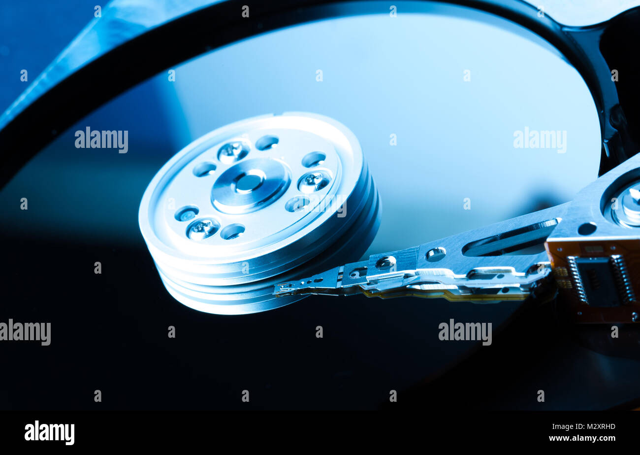 Chiudere fino all'interno di unità disco rigido. Dettaglio della scrittura/lettura di testa sul braccio attuatore e asse. Nei toni del blu dell'immagine. Foto Stock