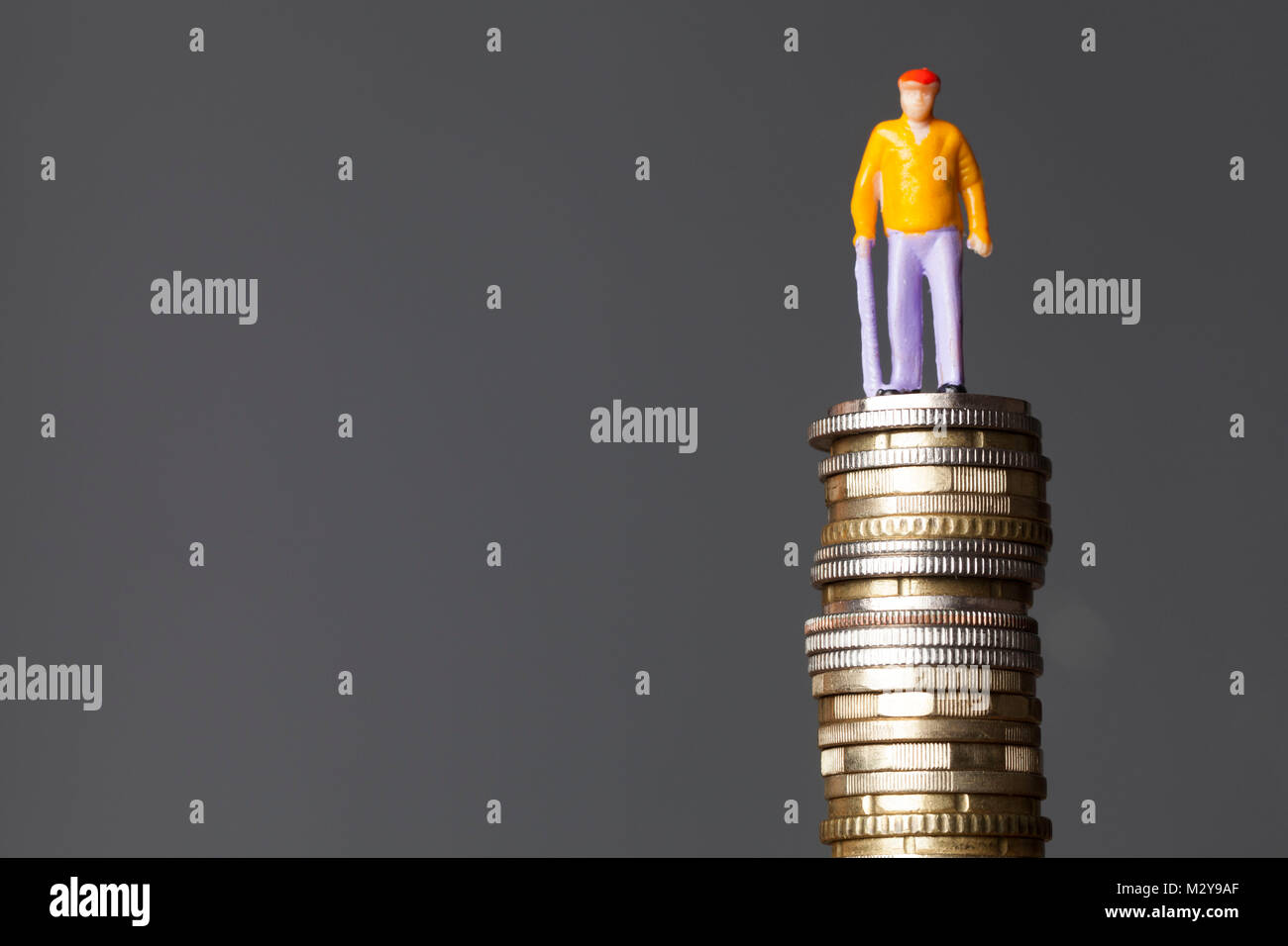 Concetto di pensione. Persona vecchia figura su una pila di monete Foto Stock