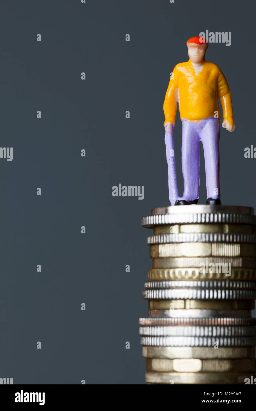 Concetto di pensione. Persona vecchia figura su una pila di monete Foto Stock