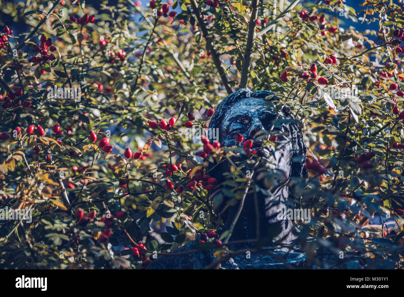 Statua di una donna circondata dal verde in un accappatoio a giornata soleggiata al Vecchio Cimitero Monumentale di Milano Italia Foto Stock