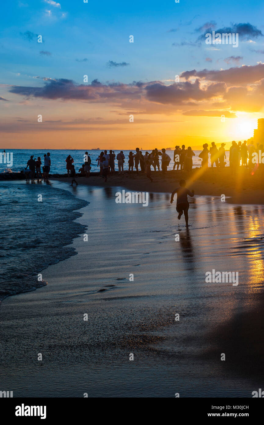 I turisti a guardare il tramonto sulla spiaggia di Waikiki di Oahu, Hawaii Foto Stock