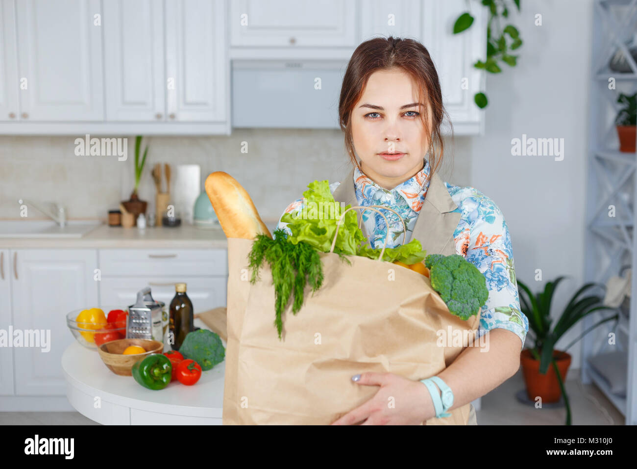 Giovani casalinga nascondendo shopping bag piena di verdure Foto Stock