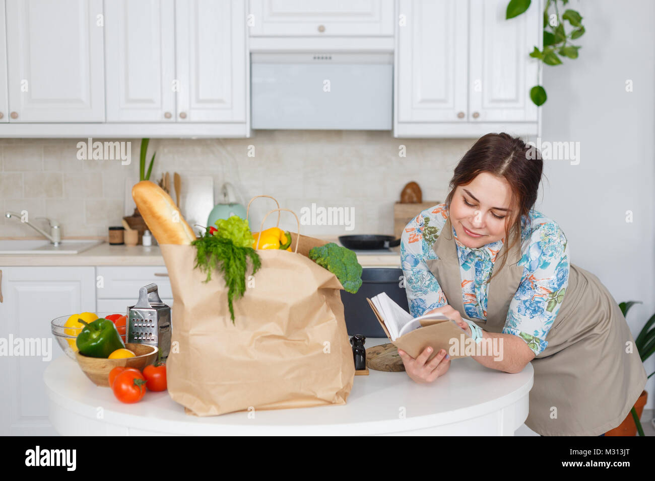 Giovani casalinga con il libro di ricette di cucina Foto Stock