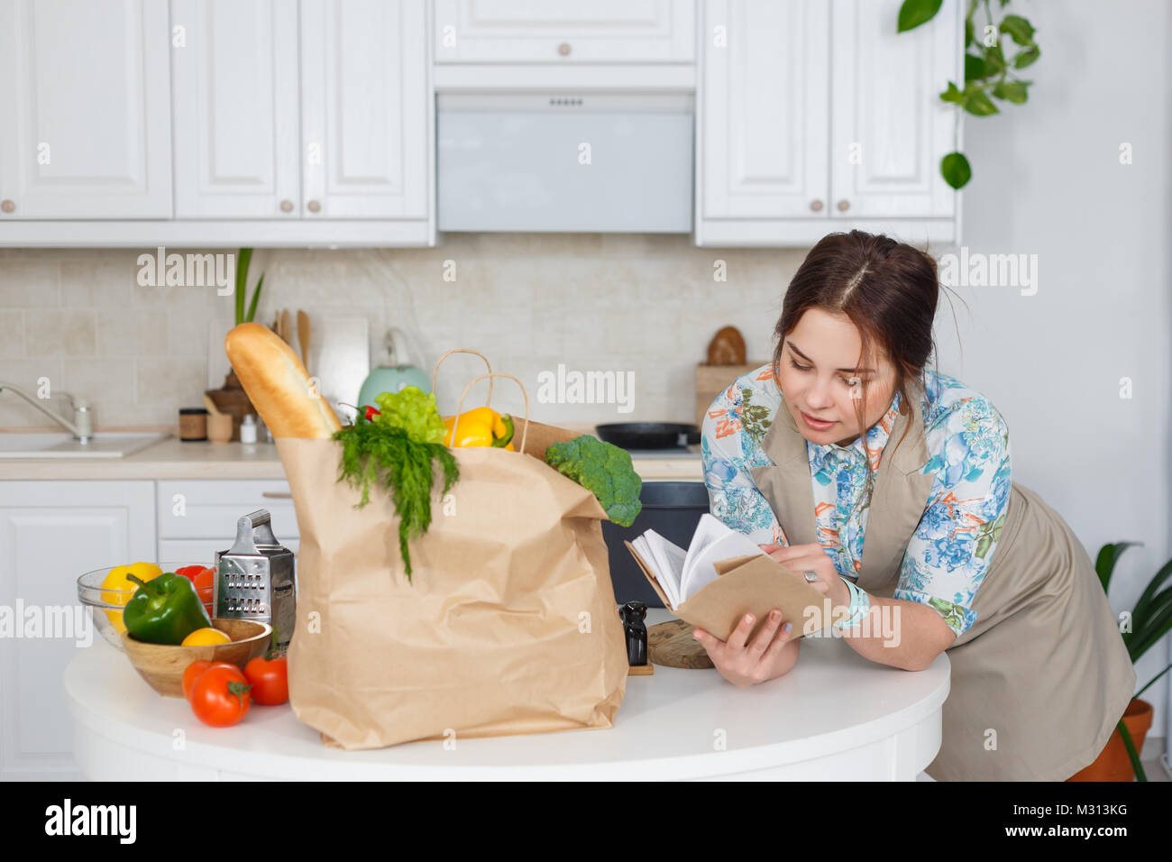 Giovani casalinga con il libro di ricette di cucina Foto Stock