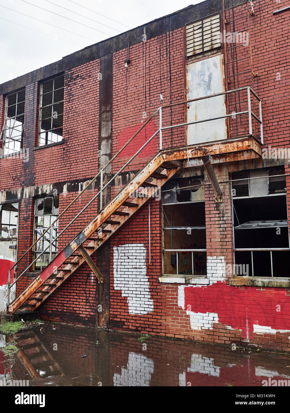 Secondo piano fire escape esterno di una corsa verso il basso edificio abbandonato che è la formazione di ruggine e parte del degrado urbano a Montgomery in Alabama USA. Foto Stock