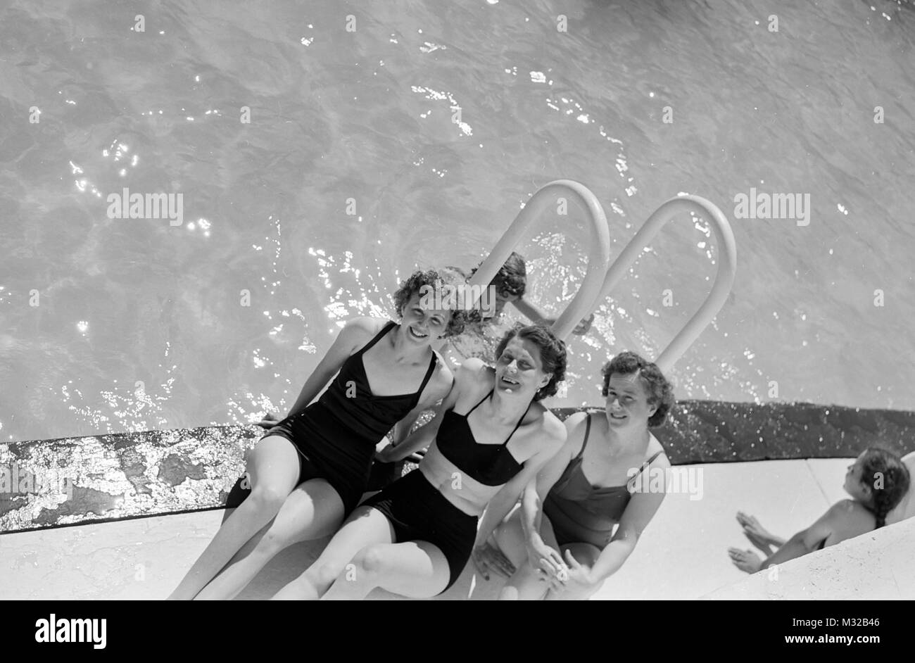 Tre giovani donne sono a lato piscina, ca. 1955. Foto Stock