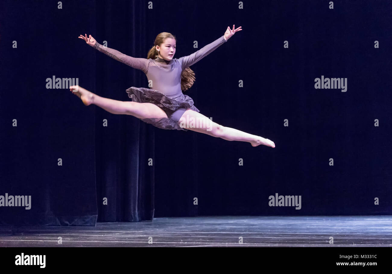 Ragazza di dodici anni sul palco di ballo facendo un cavallo di salto Foto Stock