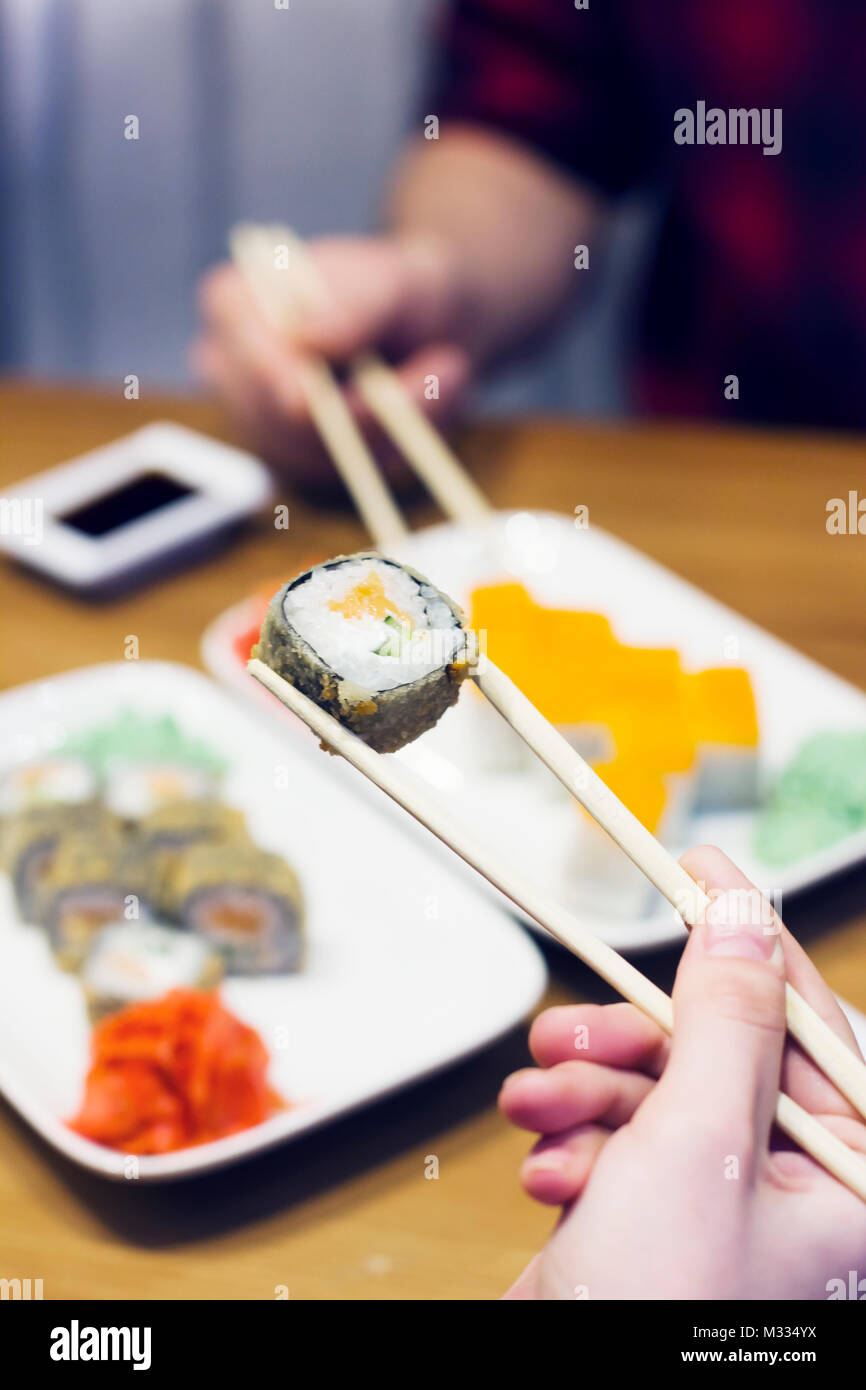 Sushi rotoli sulla piastra, amici prendendo rotoli Foto Stock