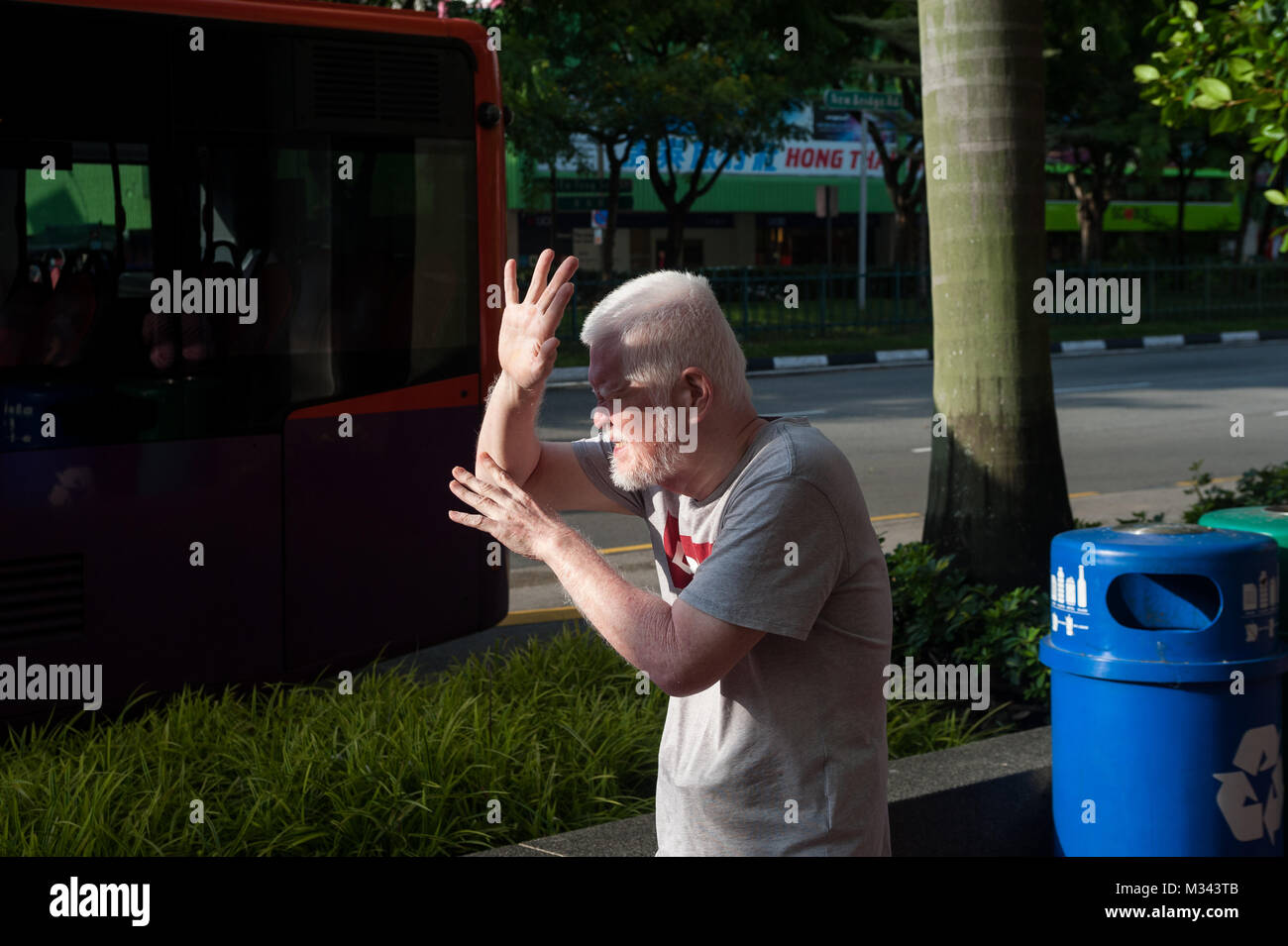 21.12.2017, Singapore, Repubblica di Singapore, in Asia - un uomo è visto la schermatura il suo volto da bassa sun a Singapore il quartiere Chinatown. Foto Stock