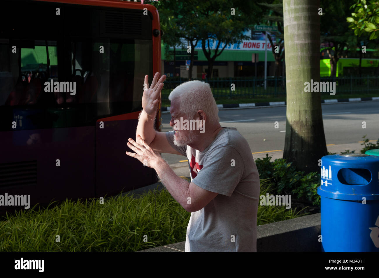 21.12.2017, Singapore, Repubblica di Singapore, in Asia - un uomo è visto la schermatura il suo volto da bassa sun a Singapore il quartiere Chinatown. Foto Stock