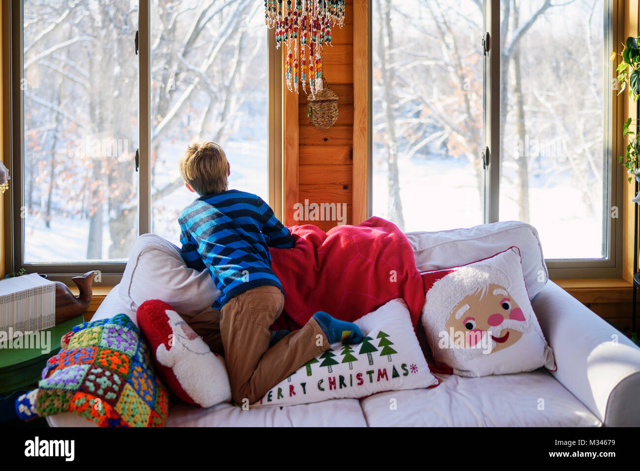 Ragazzo che guarda fuori da una finestra a Natale la neve Foto Stock