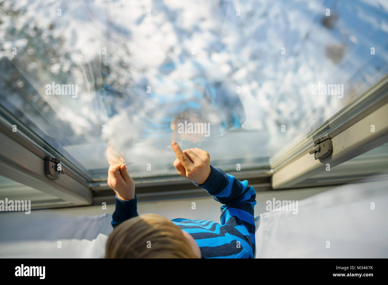 Ragazzo che guarda fuori da una finestra a neve Foto Stock