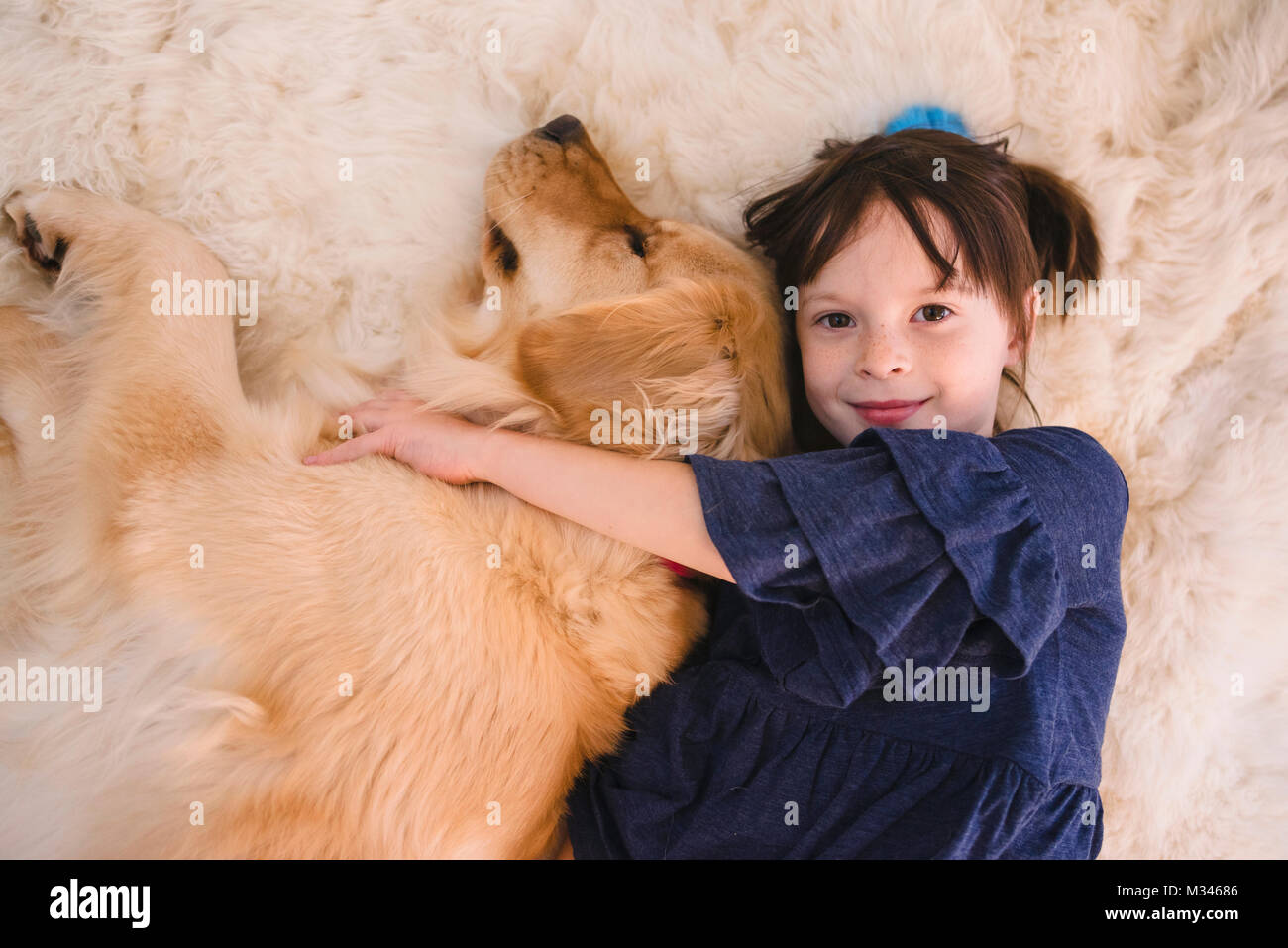 Ragazza distesa sul pavimento a giocare con il suo golden retriever cane Foto Stock