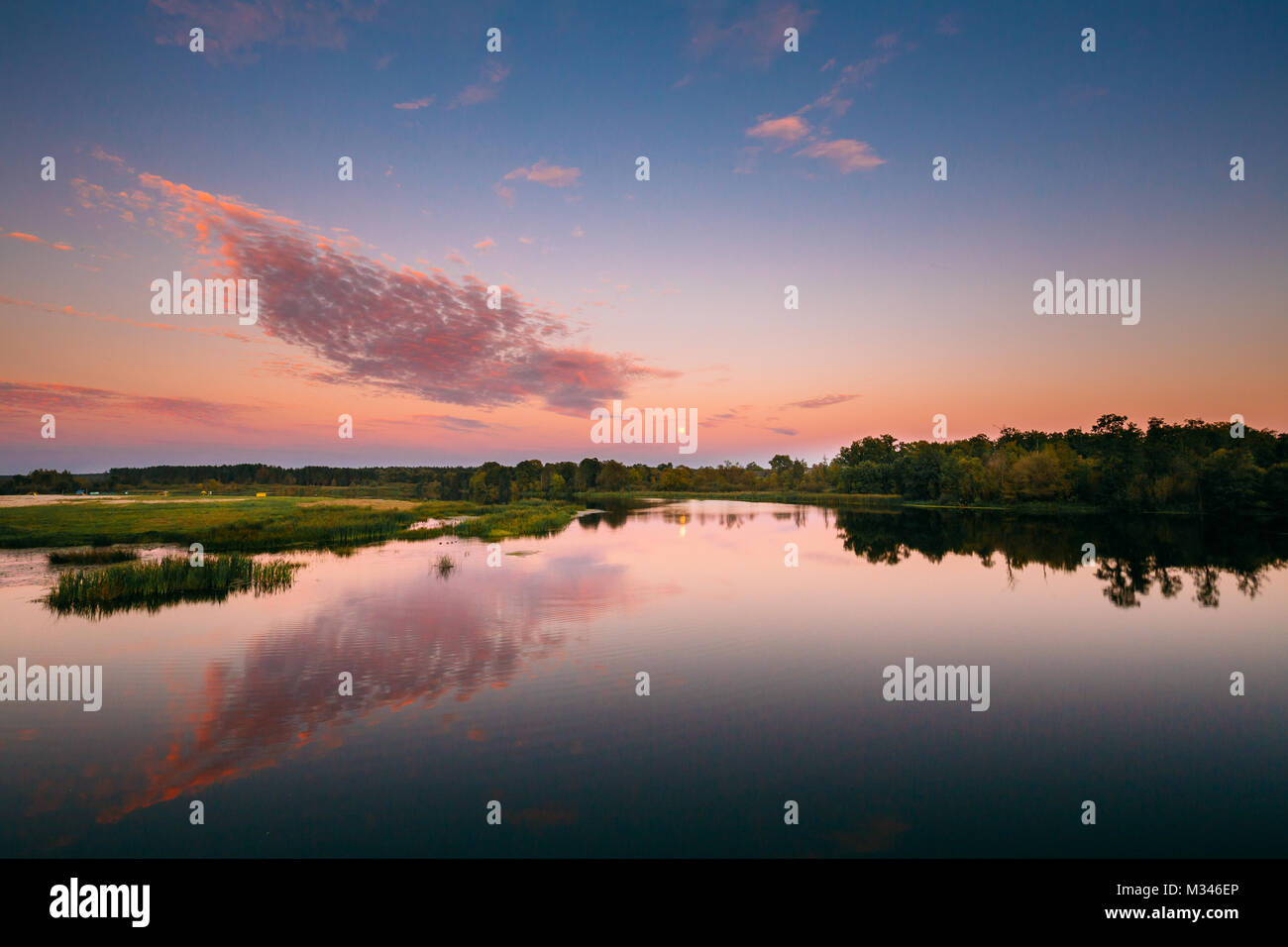 Paesaggio fluviale in Bielorussia o la parte europea della Russia nel tempo al tramonto di sera d'estate. Luna crescente per l'acqua del lago o fiume. La natura a Sunny sera. Foto Stock