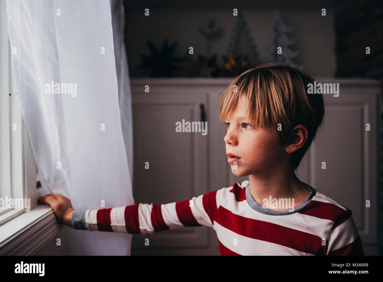 Ragazzo che guarda fuori da una finestra Foto Stock