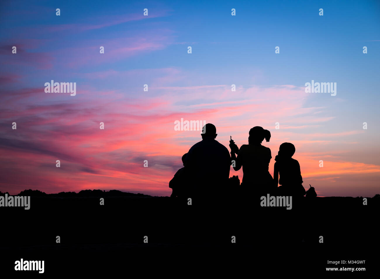 Silhouette di una famiglia godendo di uno splendido tramonto Foto Stock