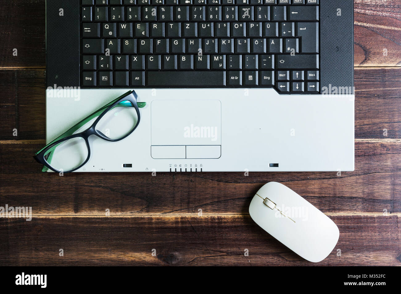 Vista superiore della roba per ufficio con notebook wireless mouse e occhiali sul tavolo in legno.Concetto workplace Foto Stock