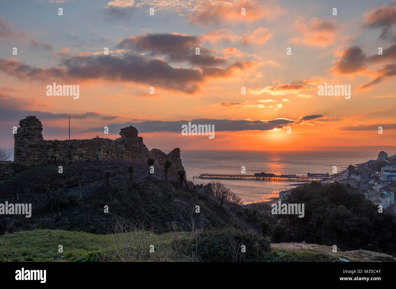 Il castello di Hastings tramonta d'inverno, con il nuovo molo e vista sulla baia fino a Beachy Head, East Sussex, Regno Unito Foto Stock