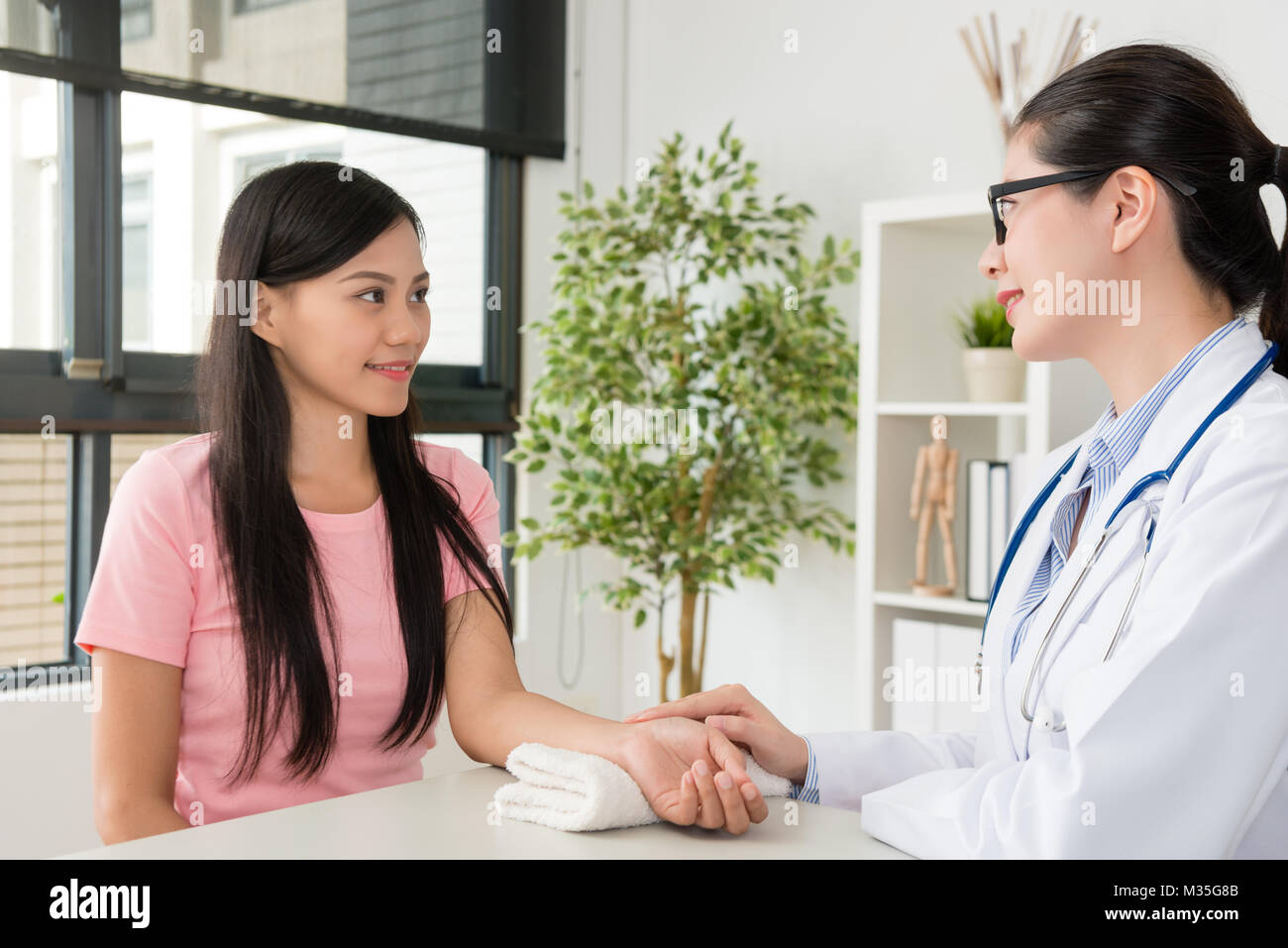 Sorridente bella donna dottore di toccare la mano del paziente per impulso di controllo prima di effettuare la diagnosi di malattia malati problema. Foto Stock