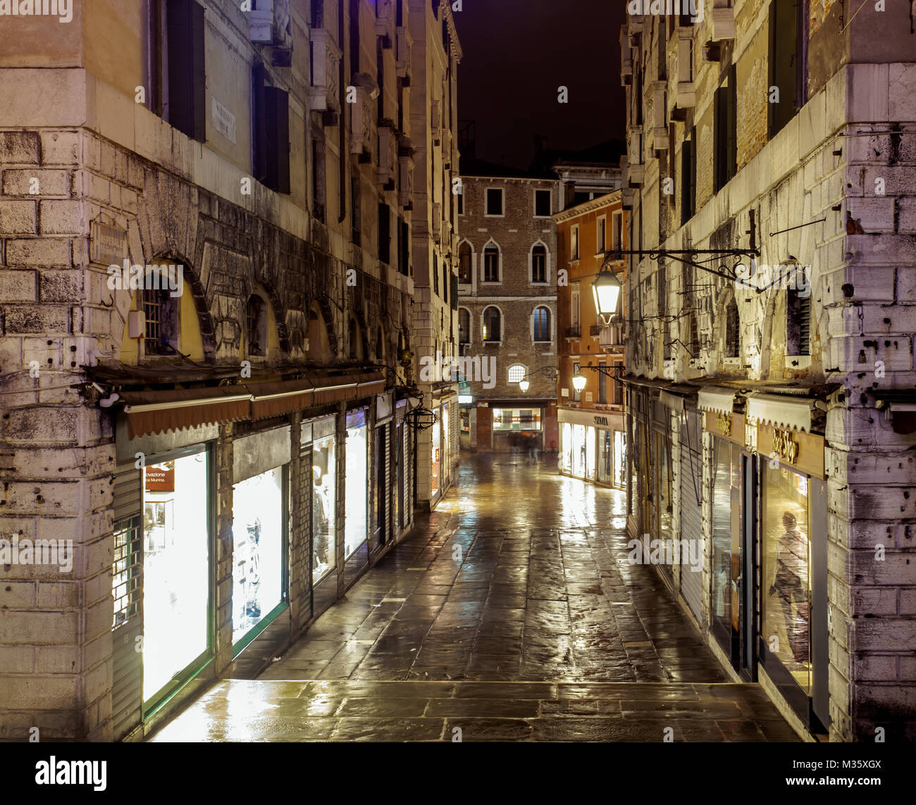 Venezia shopping alley su una serata piovosa illuminazione notturna riflessioni sulla città piovosa street Venezia Italia Foto Stock