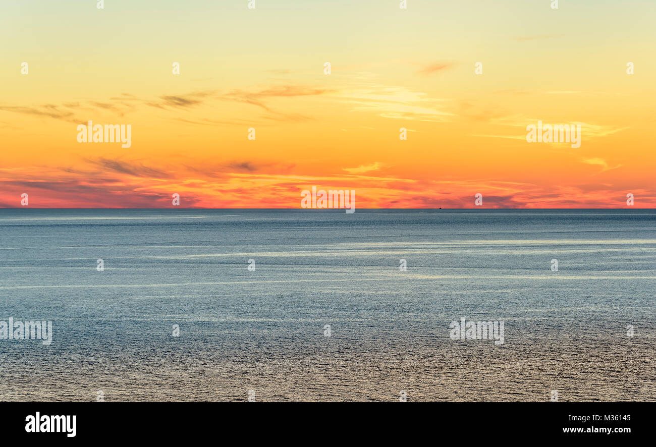 Stilizzato paesaggio astratto seascape tramonto lunga esposizione con le nuvole sotto diverse sfumature di blu, arancione, giallo e rosso. Foto Stock