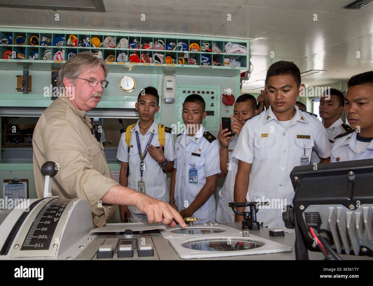 ROXAS City, Filippine (31 luglio 2015) un militare Sealift Command Chief Mate Craig Gallagher da Birmingham, Ala, spiega gli strumenti di navigazione a bordo della pilothouse della nave ospedale USNS misericordia (T-AH 19) a marittimo cadetti e personale da Colegia De La Purisima Concepcion durante un tour come parte del partenariato Pacifico 2015. I cadetti hanno ricevuto informazioni circa la nave il castello di prua, il ponte e le camere del motore. Pacific Partnership è nella sua decima iterazione ed è il più grande annuale multilaterale di assistenza umanitaria e di soccorso in caso di catastrofe preparazione missione condotta nel Indo-Asia-Pacifico r Foto Stock