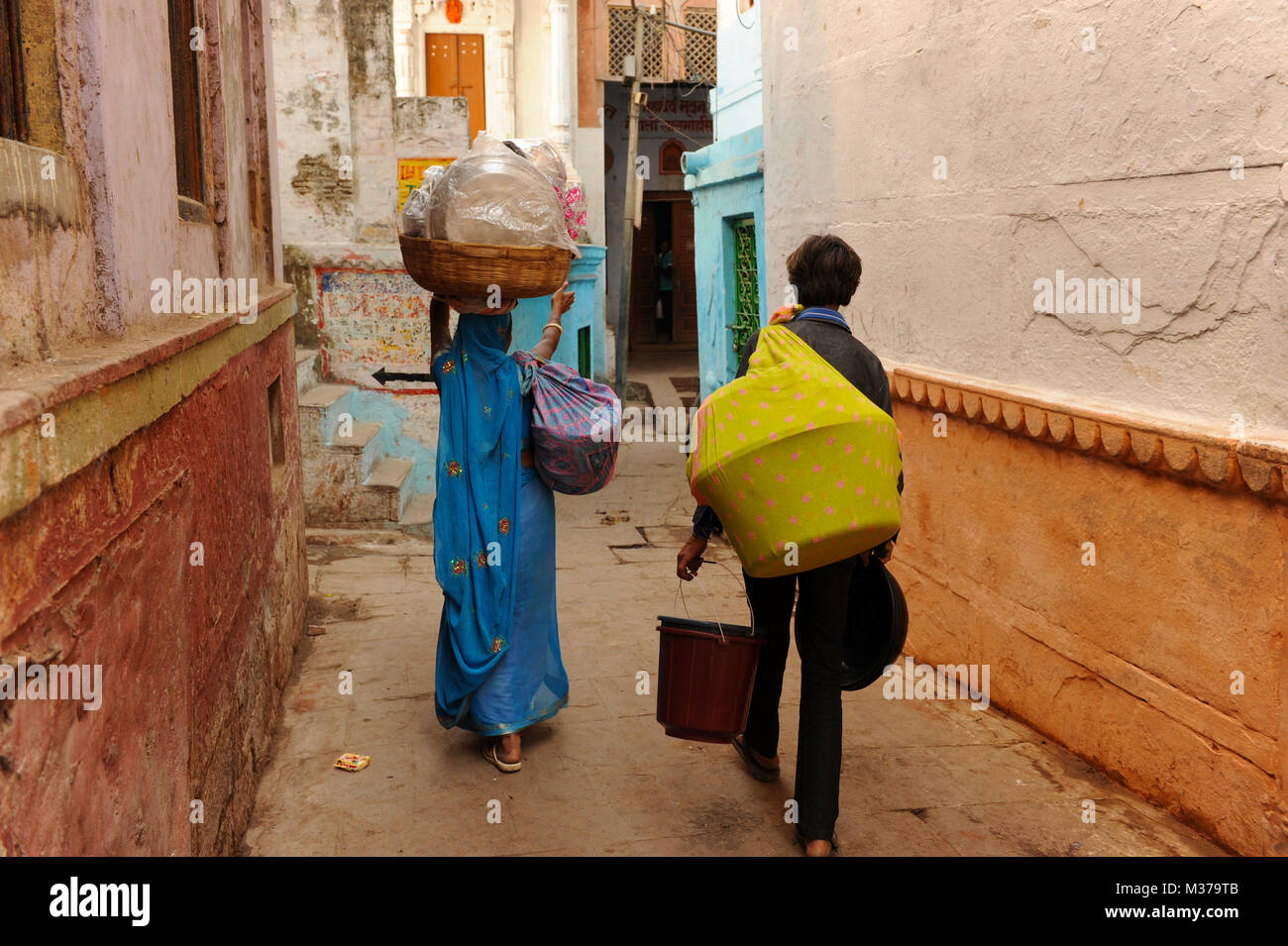 Persone trasportare merci pesanti attraverso una Varanasi Steeet, India Foto Stock