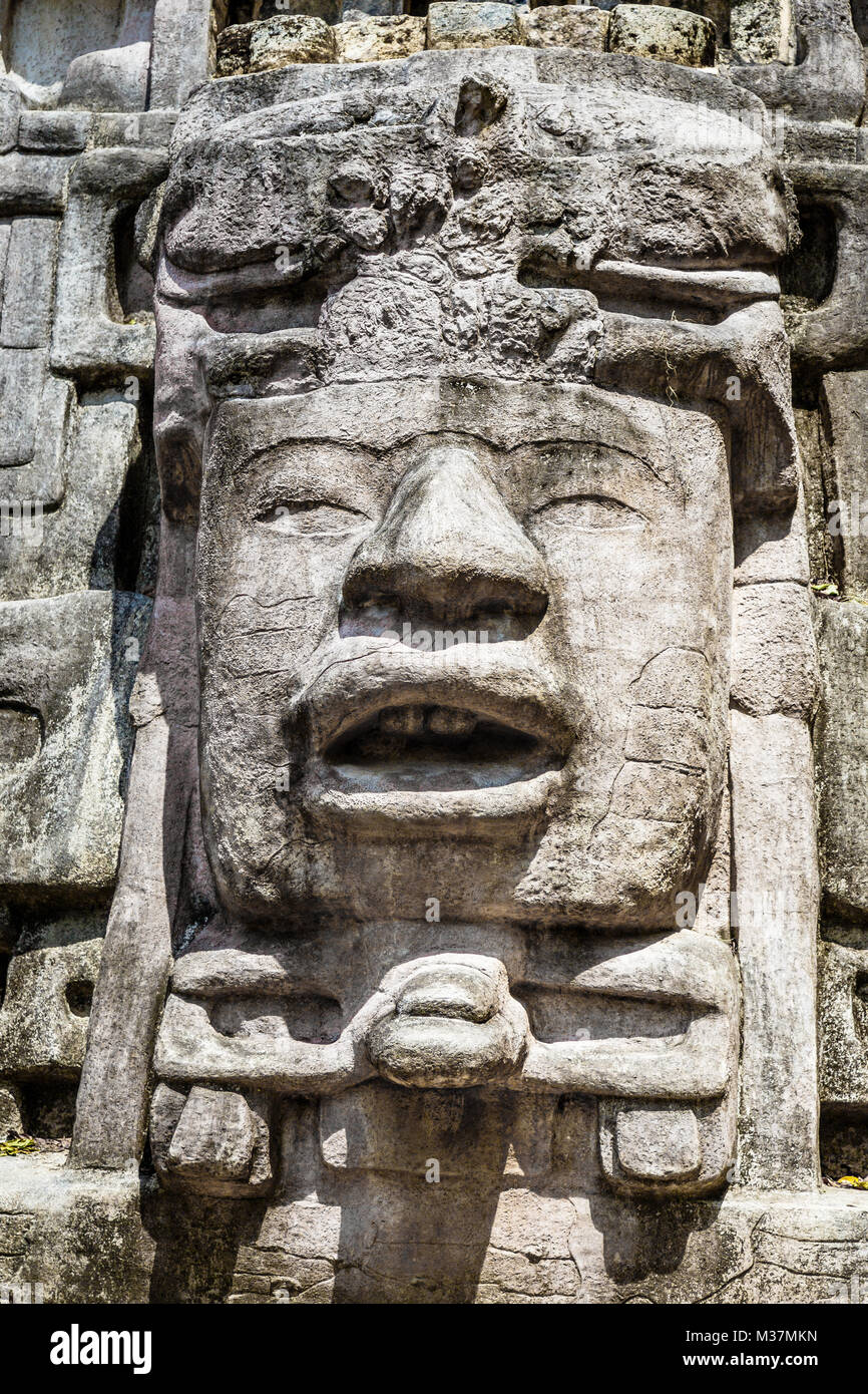 Vecchia pietra antichi Maya di civiltà precolombiane volto scolpito e ornamento, Lamanai sito archeologico, Orange Walk distretto, Belize Foto Stock