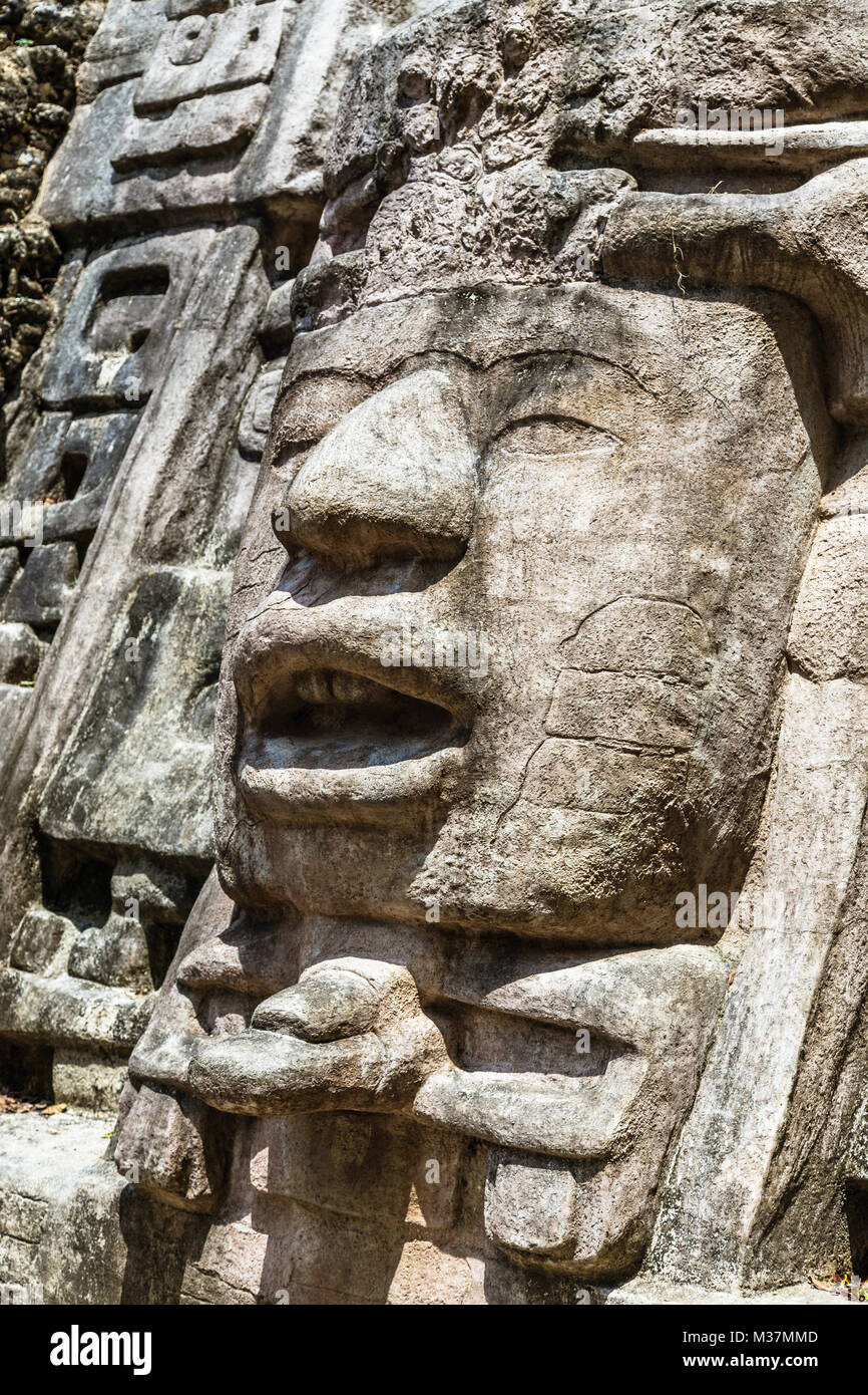 Vecchia pietra antichi Maya di civiltà precolombiane volto scolpito e ornamento, Lamanai sito archeologico, Orange Walk distretto, Belize Foto Stock
