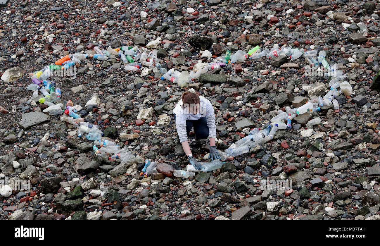 Un volontario crea un cuore di raccolta sagomato di bottiglie di plastica che inquinano il foreshore del Fiume Tamigi a Dock Queenhithe nel centro di Londra, in un evento organizzato dalla #OneLess campagna e Thames21 ad attirare l attenzione sull impatto che a uso unico in plastica le bottiglie di acqua sono avente sull'ambiente. Foto Stock