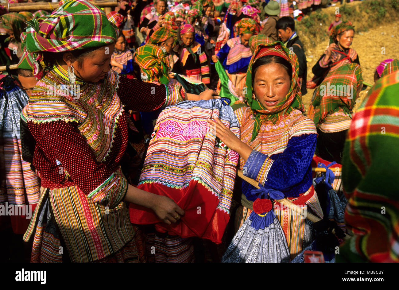 Il Vietnam. Bac Ha. Flower Hmong hilltribe. Mercato. Donne acquisto di abbigliamento tradizionale (gonne). Foto Stock