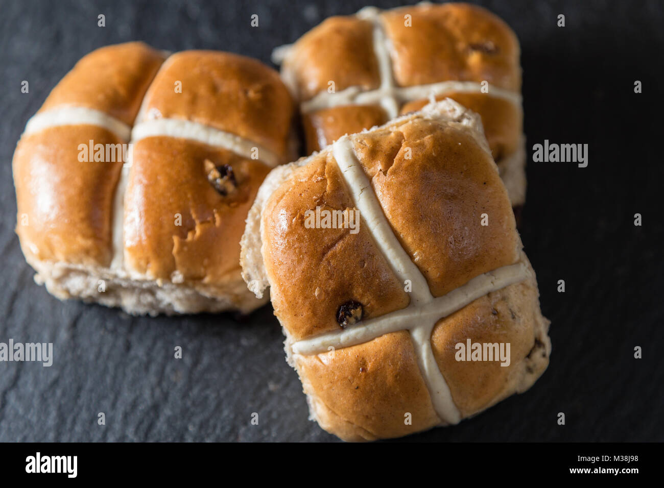 Tre hot cross i panini su una drak lastra grigia. Queste sono le tradizionali Pasqua gastronomica Foto Stock